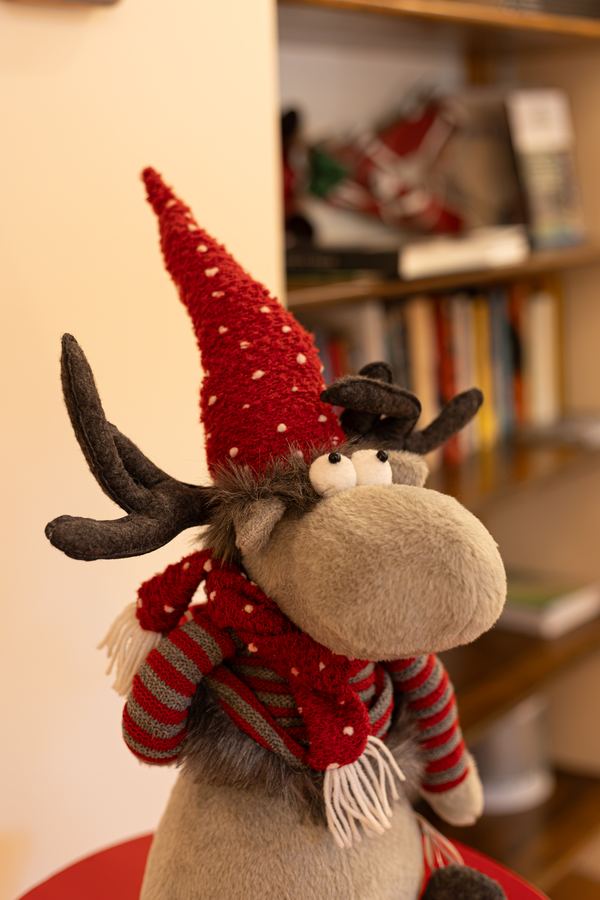 Una renna di peluche con sciarpa e cappello rosso