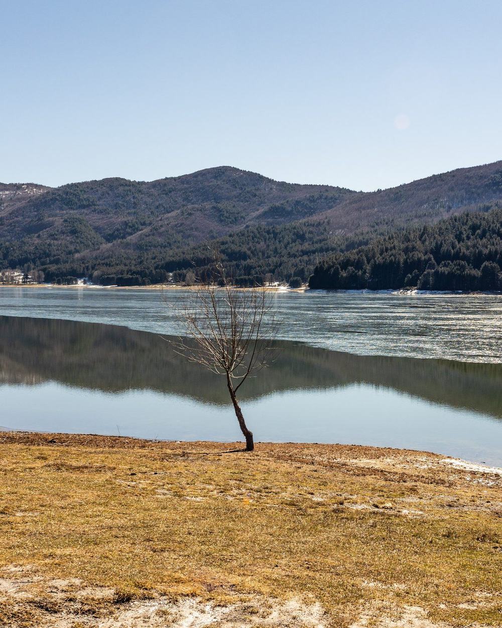 Il Lago Arvo d'inverno, in parte ghiacciato, con i monti innevati